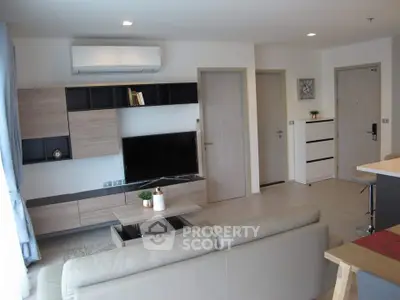 Modern living room with sleek furniture and neutral tones, featuring a wall-mounted TV and air conditioning.