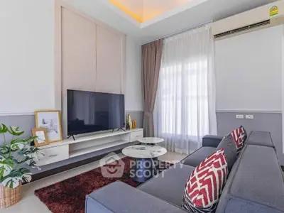 Modern living room with stylish decor and large TV, featuring cozy seating and elegant lighting.