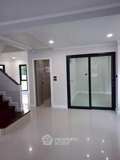 Spacious modern interior with sleek staircase and glass doors, perfect for contemporary living.
