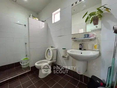 Modern bathroom with sleek fixtures and tiled flooring, featuring a shower area and a wall-mounted sink.