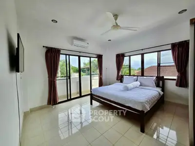 Spacious bedroom with large windows and balcony access, offering natural light and scenic views.