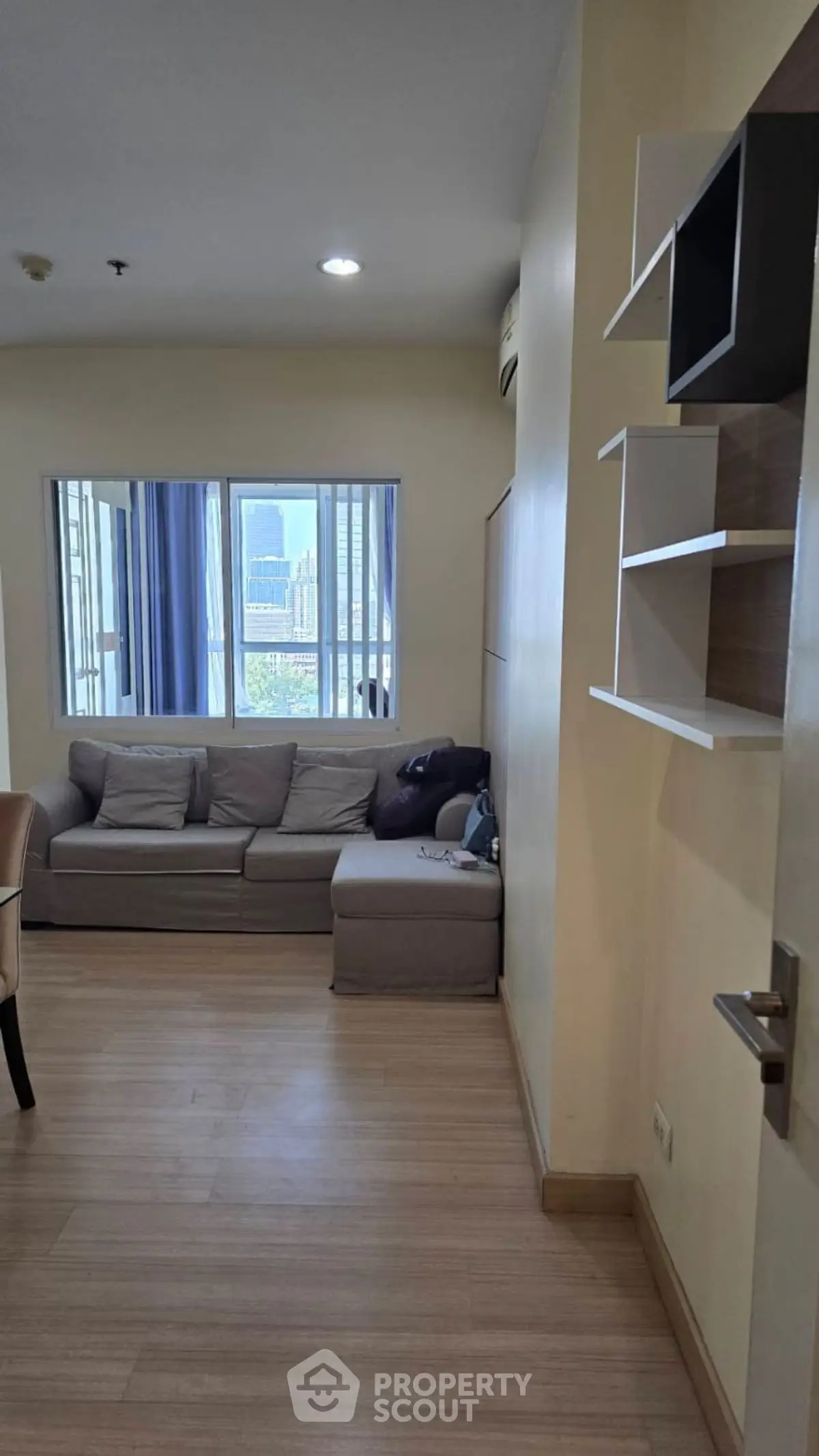 Cozy living room with city view, featuring a comfortable sofa and modern shelving.