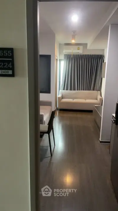 Modern apartment interior with sleek wooden flooring and cozy living area, featuring a stylish sofa and elegant curtains.