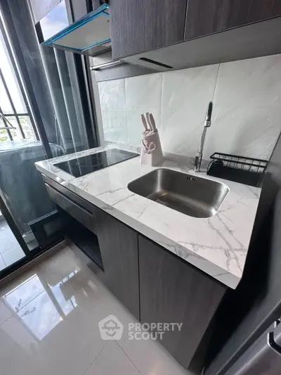 Modern kitchen with sleek marble countertop and stainless steel sink in a stylish apartment.