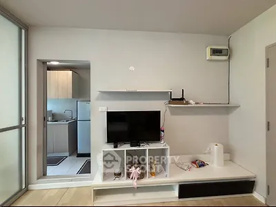 Modern living room with sleek TV unit and adjacent kitchen area in a stylish apartment.