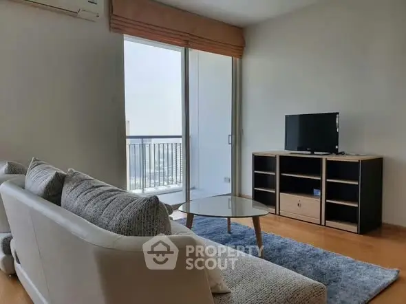 Modern living room with balcony view, featuring cozy sofa and sleek TV stand.