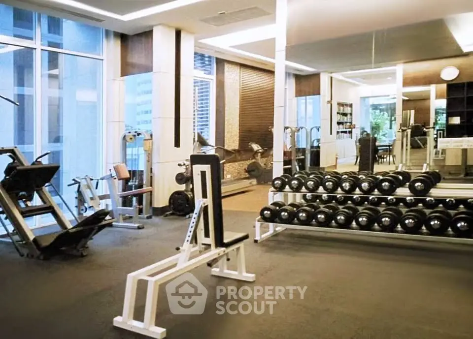 Modern gym with state-of-the-art equipment and large mirrors in luxury apartment building.