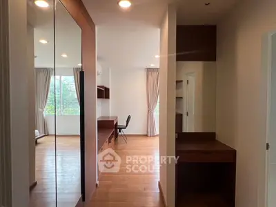 Spacious bedroom with wooden flooring and large windows offering natural light.