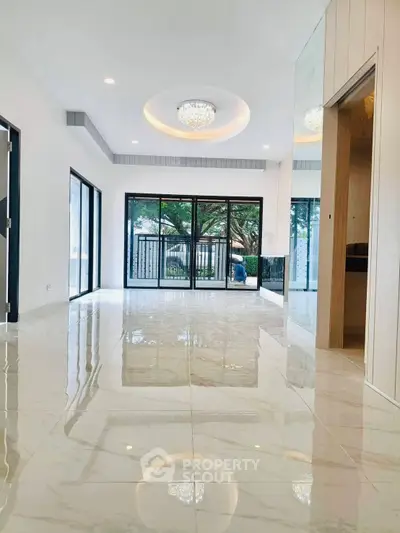 Spacious modern living room with glossy marble floors and large windows offering garden views.