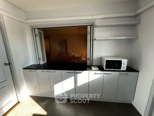 Modern kitchen with sleek cabinets and microwave, featuring open layout and ample storage.