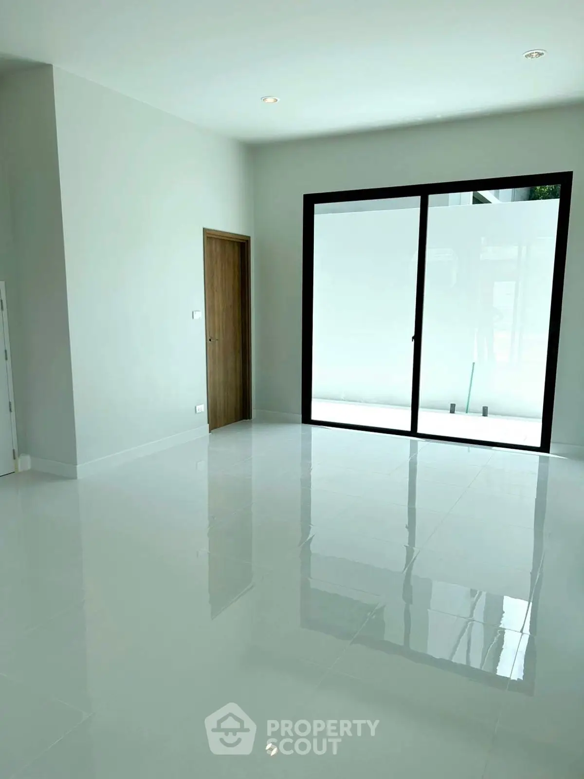Spacious modern room with glossy white tiles and large sliding glass doors.