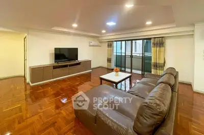 Spacious living room with modern furniture and large TV, featuring polished wooden floors.
