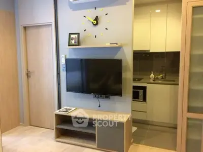 Modern compact living room with wall-mounted TV and sleek kitchen area.