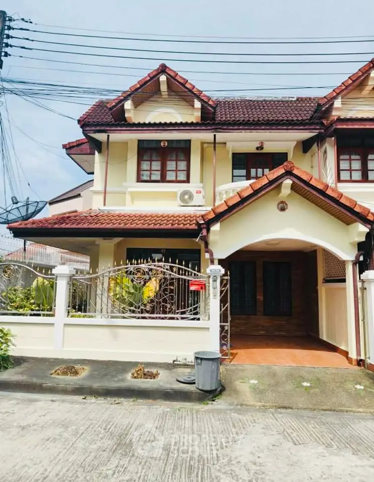 Charming two-story house with red-tiled roof and gated entrance in a suburban neighborhood.