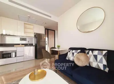 Modern living room with stylish kitchen, featuring sleek appliances and cozy seating area.