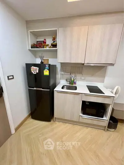 Modern compact kitchen with sleek black fridge and built-in microwave