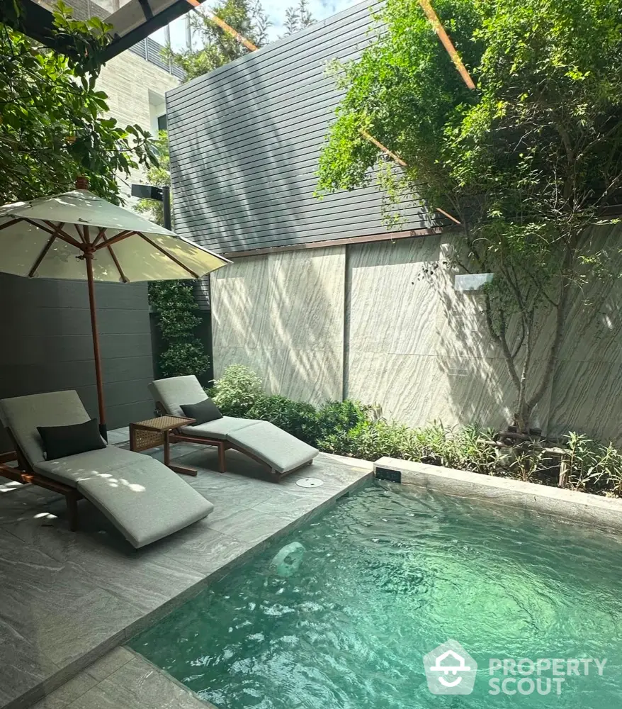 Luxurious private pool with sun loungers and lush greenery in modern backyard oasis.