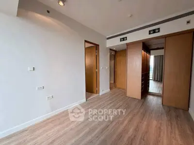Spacious modern bedroom with wooden flooring and built-in closet, perfect for stylish living.