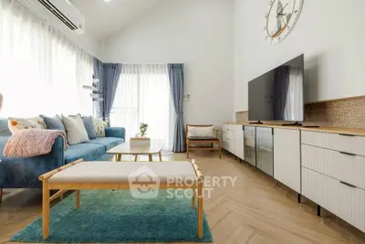 Modern living room with stylish decor, large windows, and cozy seating area.