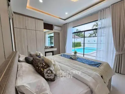 Luxurious bedroom with pool view, elegant decor, and abundant natural light.