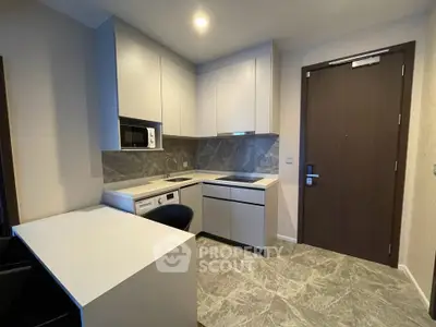 Modern compact kitchen with sleek cabinetry and integrated appliances in a stylish apartment.