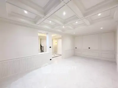 Spacious empty room with elegant coffered ceiling and bright white walls, perfect for customization.