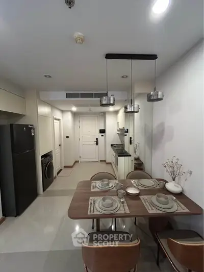 Modern kitchen with dining area, featuring sleek appliances and stylish lighting in a contemporary apartment.