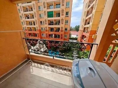 Charming balcony view in vibrant apartment complex with lush garden and pool.