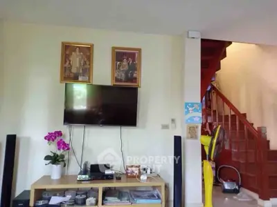 Cozy living room with TV and staircase, ideal for family gatherings.