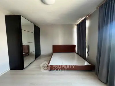 Spacious bedroom with modern wardrobe and large windows for natural light.