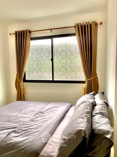 Cozy bedroom with elegant curtains and frosted window for privacy.