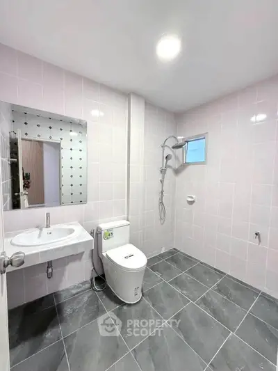 Modern bathroom with sleek fixtures and tiled walls, featuring a spacious shower area and contemporary design.