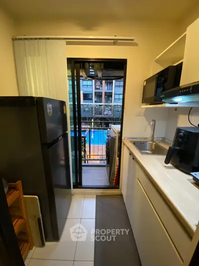 Compact kitchen with balcony view overlooking pool in modern apartment