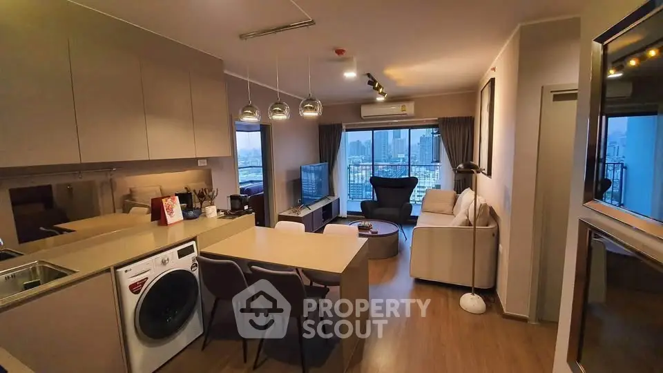Modern open-layout living room with kitchen, featuring city view and stylish decor.