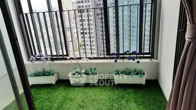 Charming balcony with artificial grass and flower pots offering a serene city view, perfect for relaxation.