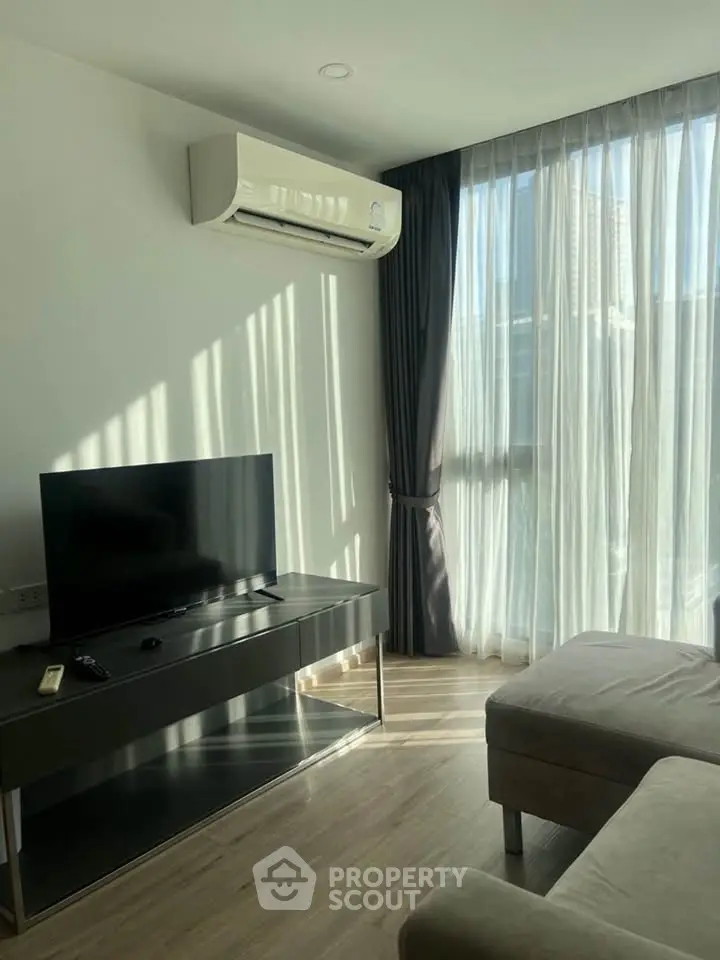 Modern living room with natural light, sleek furniture, and air conditioning.