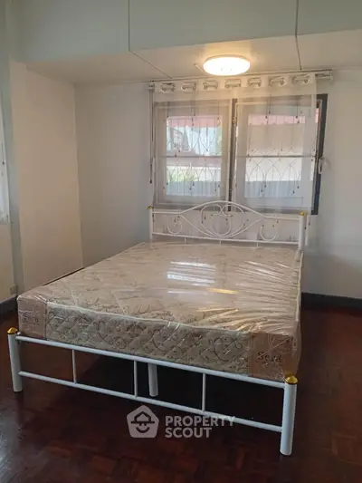 Spacious bedroom with elegant bed and natural light from large windows.