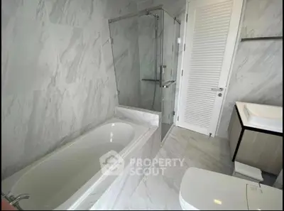 Luxurious modern bathroom with elegant marble design and glass shower enclosure.