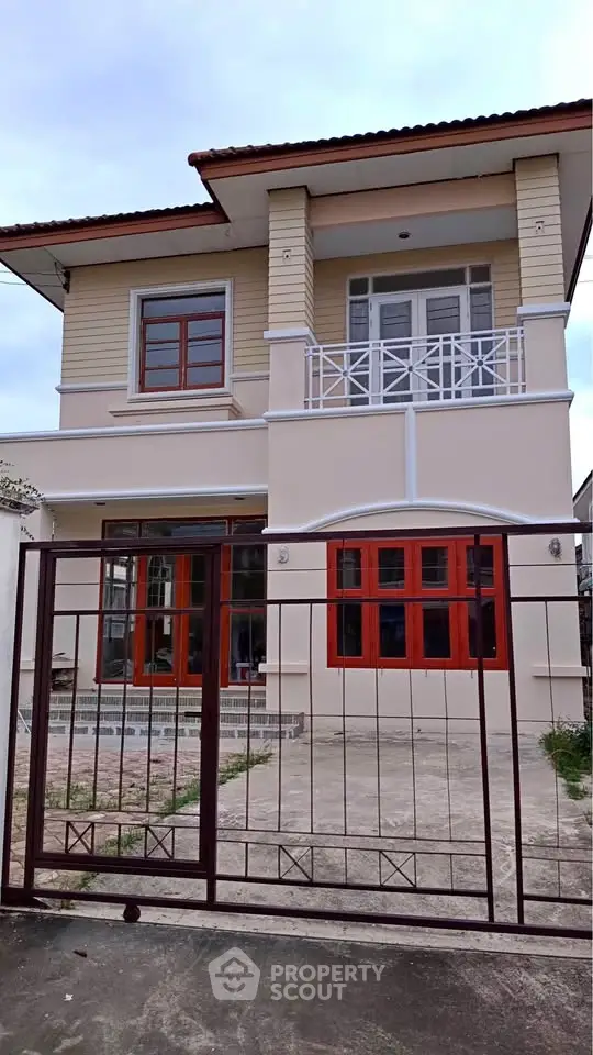 Charming two-story house with balcony and gated entrance, perfect for family living.