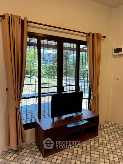 Cozy living room with window view and TV stand, perfect for relaxation.