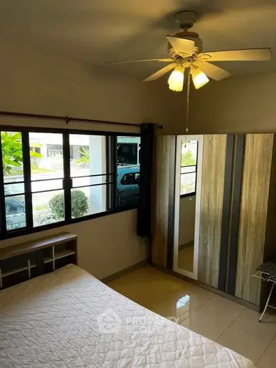 Cozy bedroom with ceiling fan and large window offering natural light