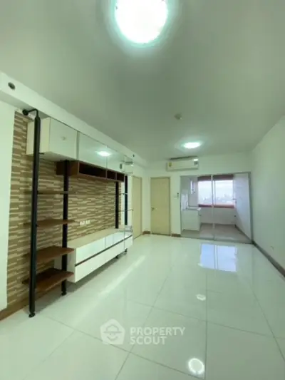 Spacious and bright living room with modern shelving units, glossy tiled flooring, and ample natural light from large windows, perfect for family gatherings and entertainment.