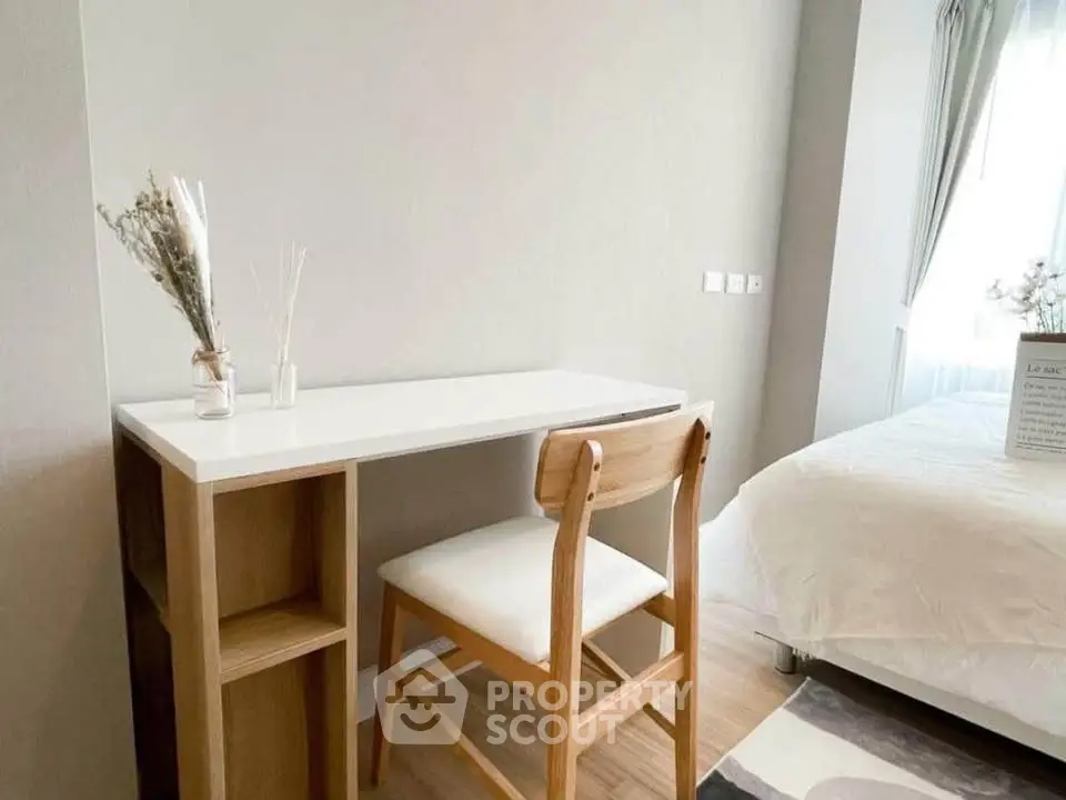Modern bedroom with minimalist desk and chair, bright natural light, and cozy decor.