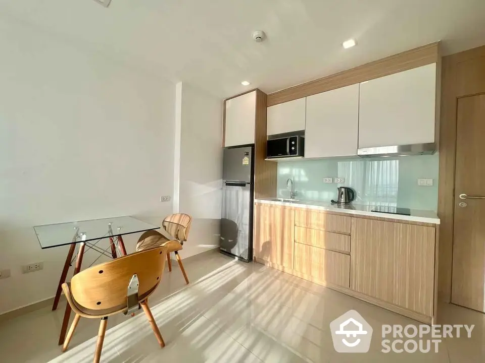 Modern kitchen with sleek cabinetry and dining area in bright apartment