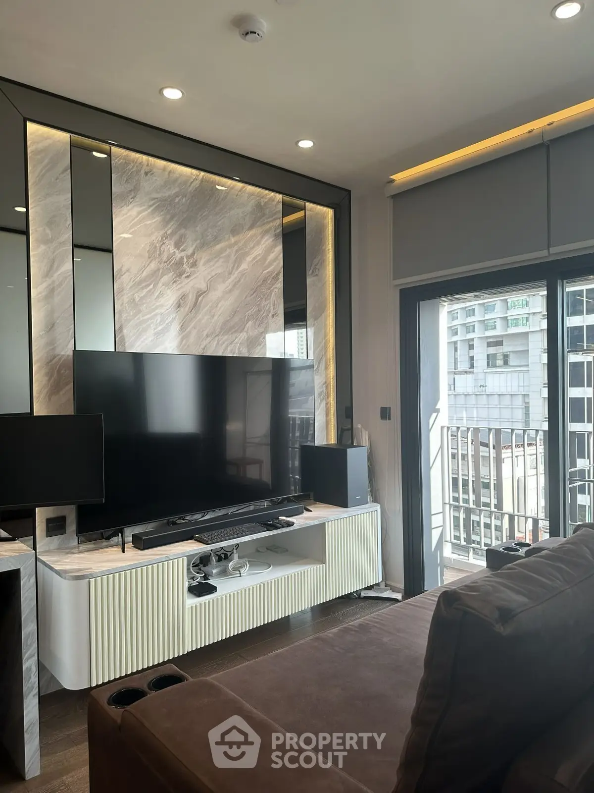 Modern living room with sleek TV setup and balcony view in urban apartment