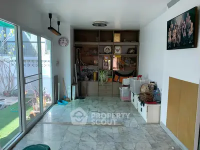 Spacious living area with marble flooring and sliding glass doors leading to a garden.