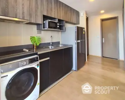 Modern kitchen with sleek appliances and wooden cabinetry in a stylish apartment.