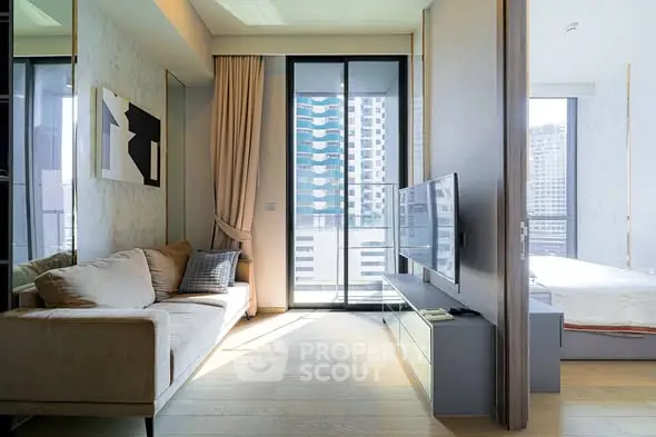 Modern living room with large windows and city view, featuring a cozy sofa and sleek TV setup.