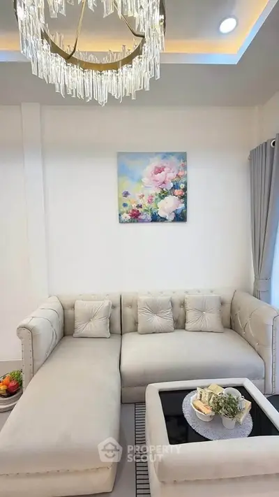 Elegant living room with plush sofa, modern chandelier, and floral artwork, perfect for stylish relaxation.