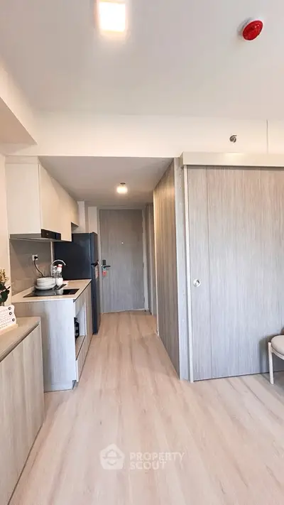Modern kitchen with sleek cabinetry and light wood flooring in a compact apartment.